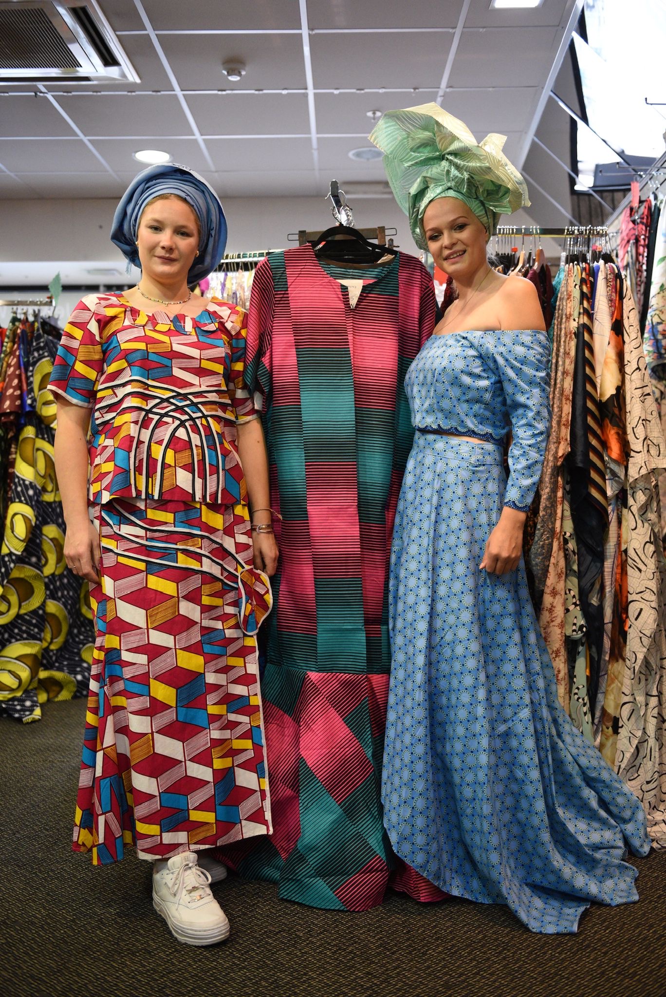 Two guests in traditional attire beside a clothing display
