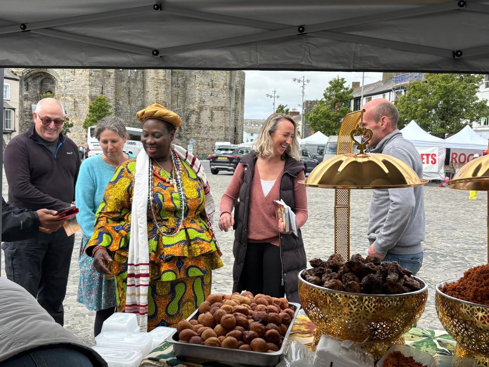 Community members sharing food at an outdoor market stall